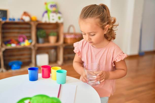 Beautiful blond toddler girl drinking glass of water at kindergarten Beautiful blond toddler girl drinking glass of water at kindergarten